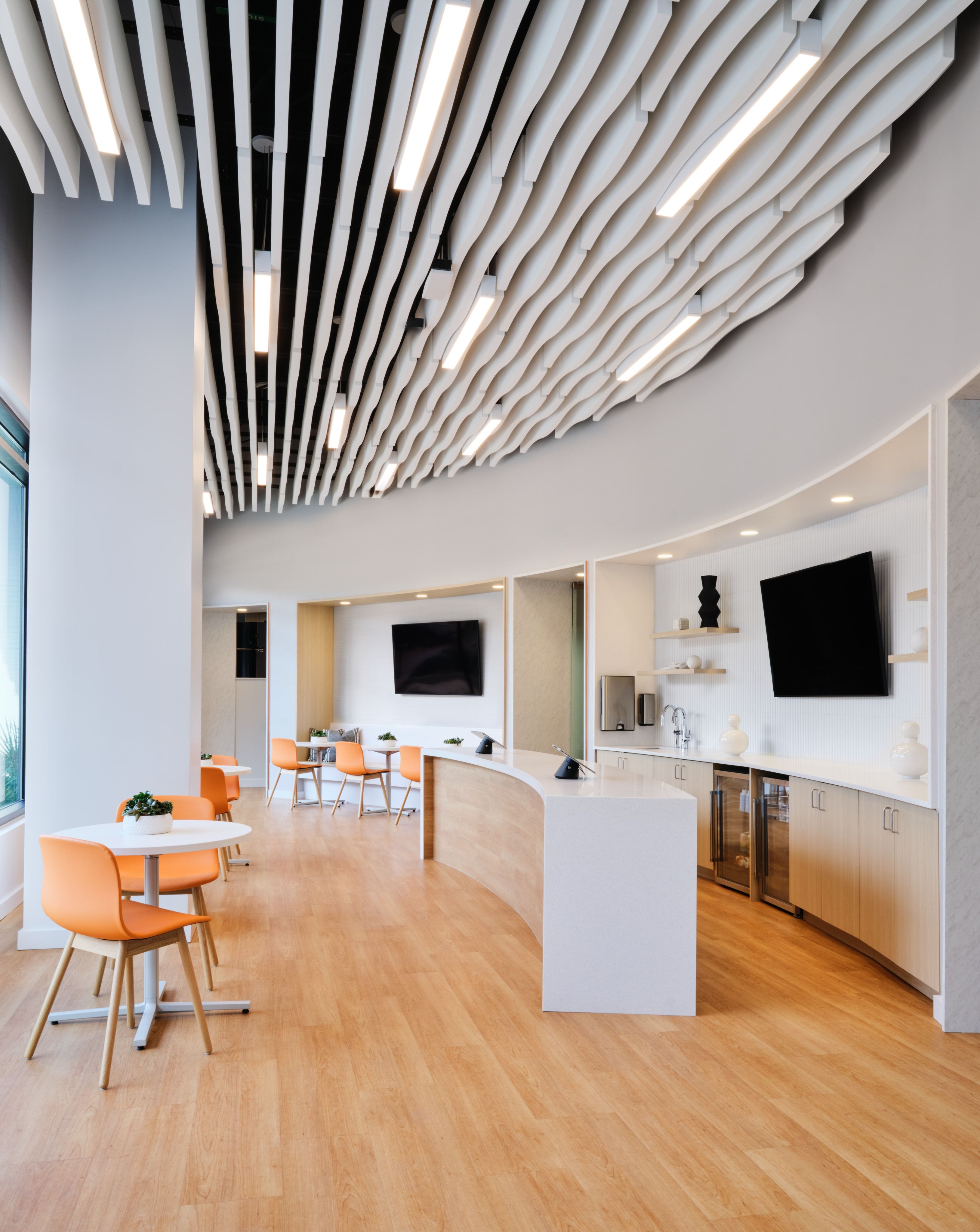 Member kitchen and lounge with curved sculptural ceiling and orange chairs