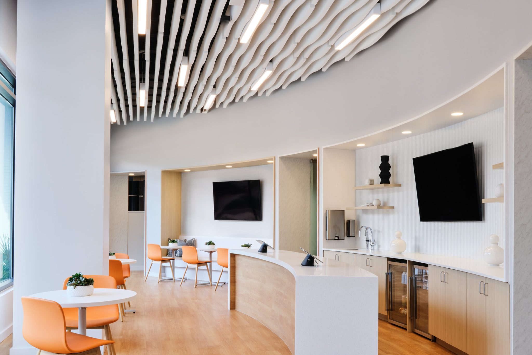 Member kitchen and lounge with curved sculptural ceiling and orange chairs