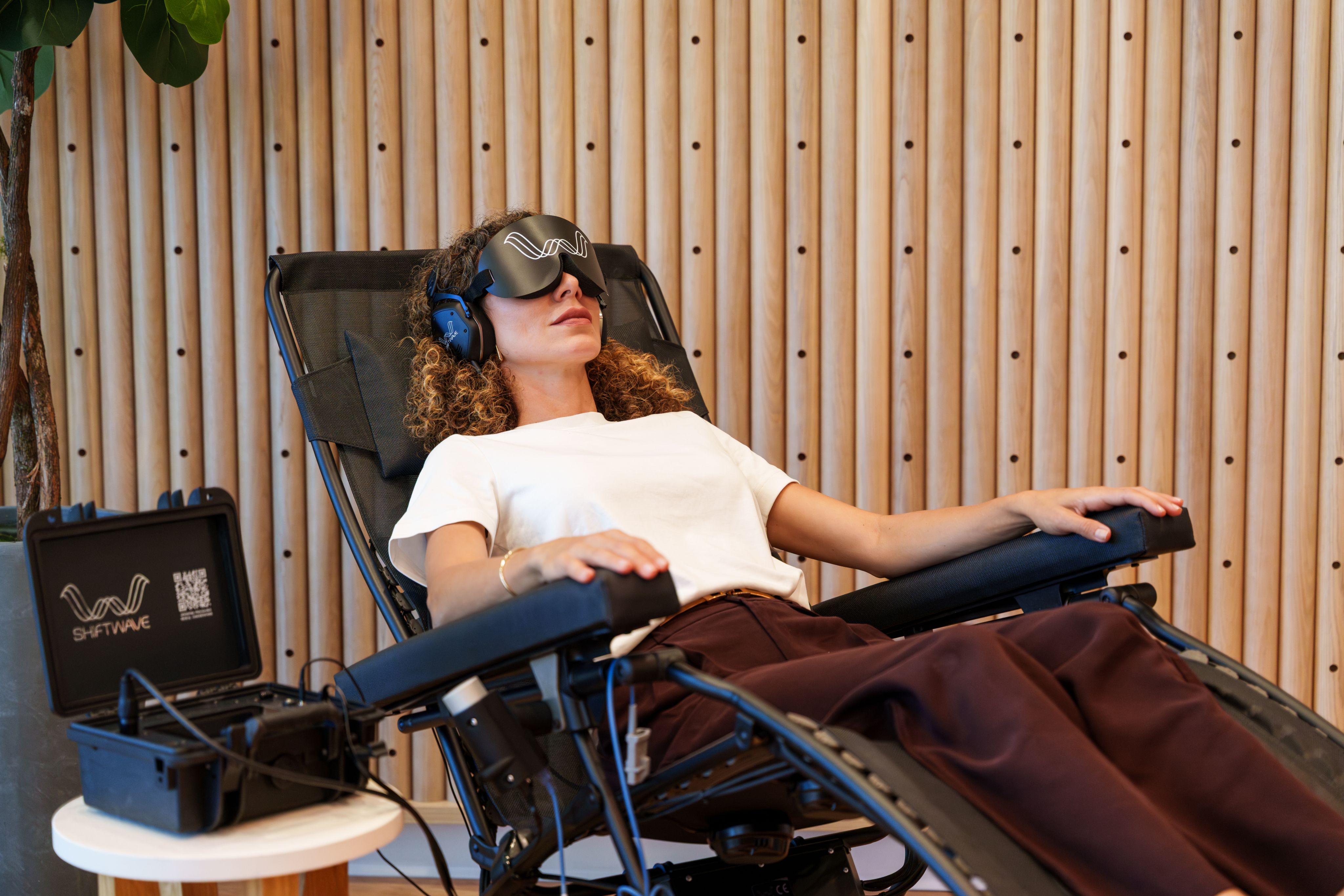 A woman reclines in a treatment chair during a Shiftwave session