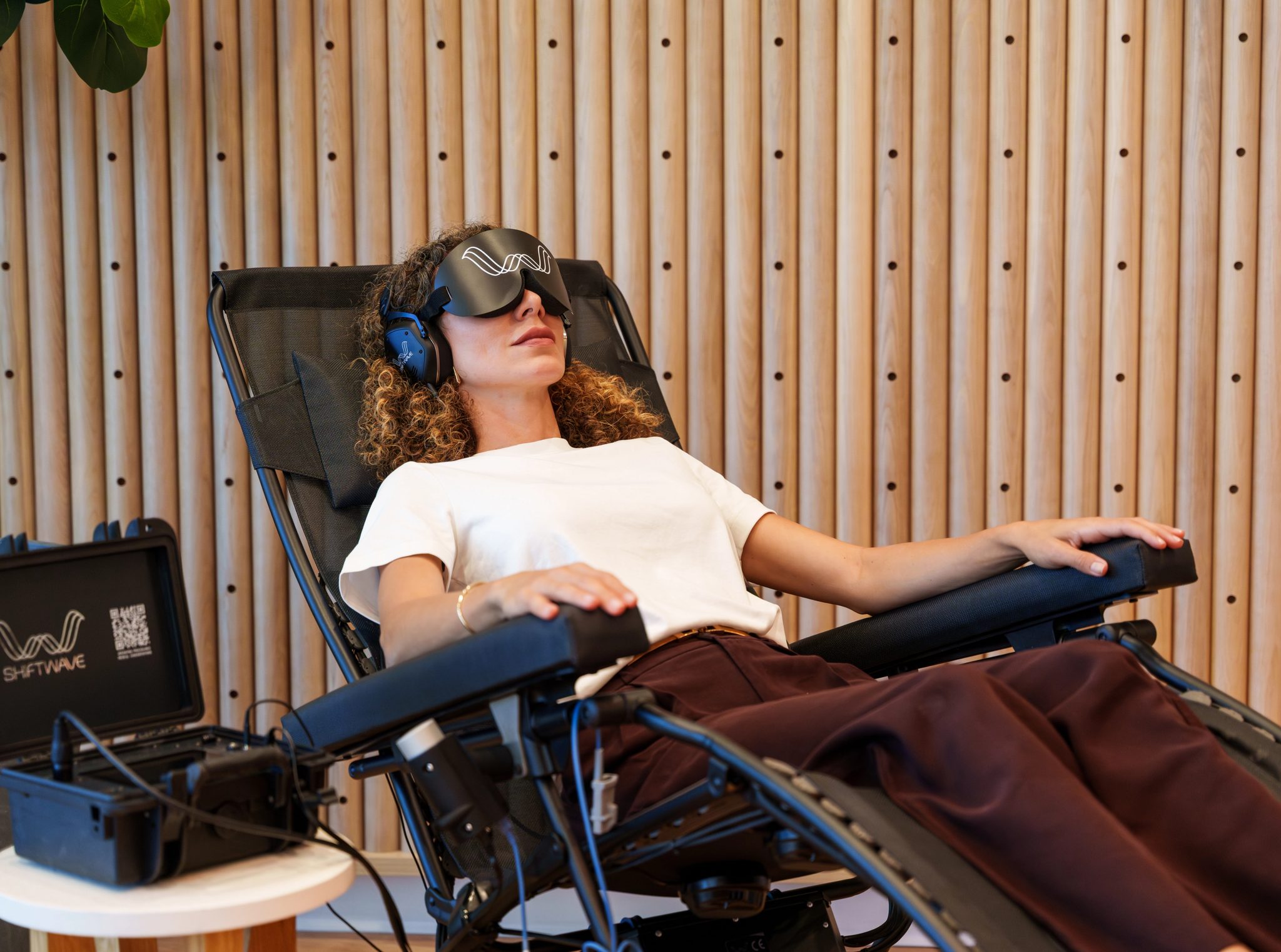 A woman reclines in a treatment chair during a Shiftwave session