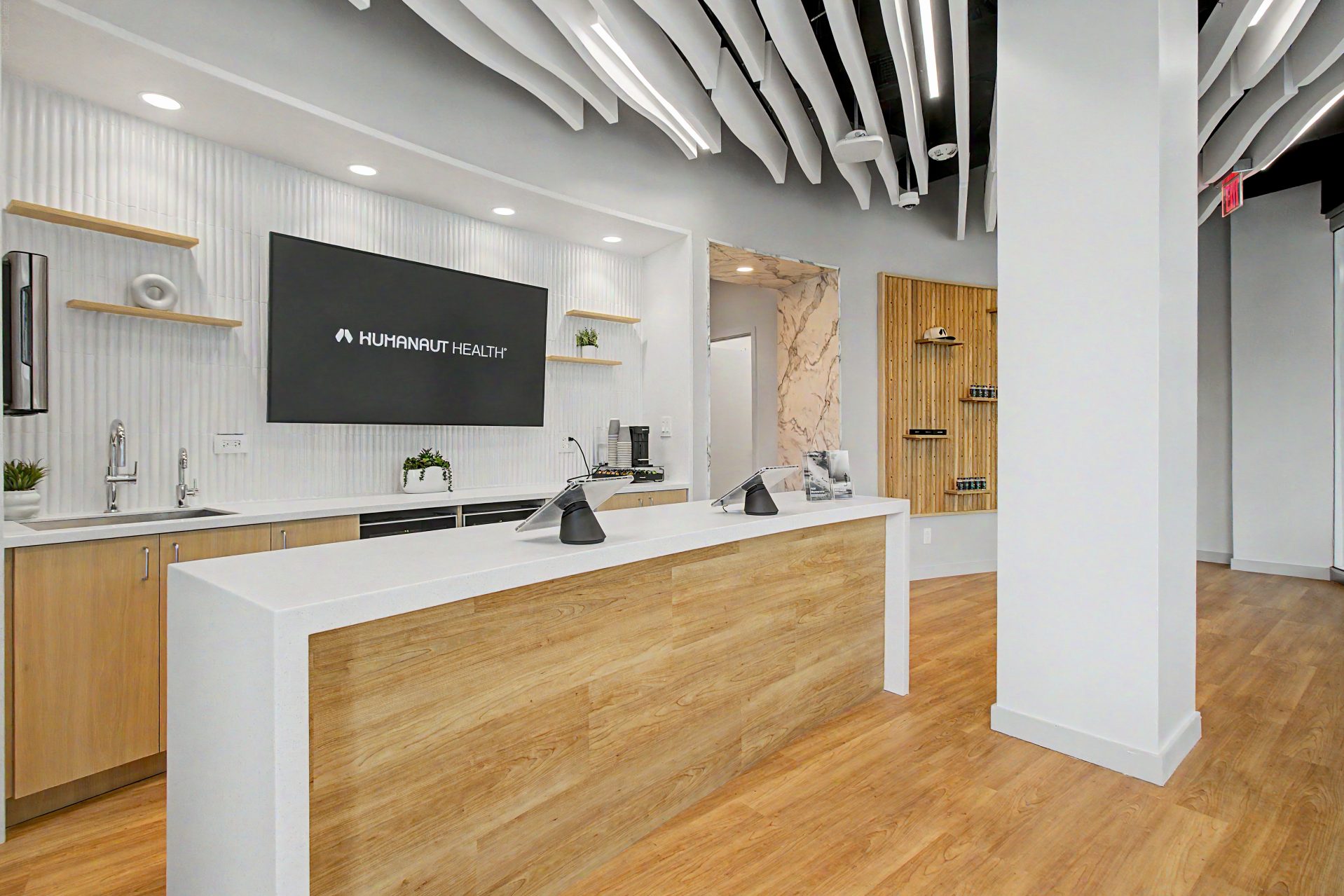 Reception desk with Humanaut Health display and curved ceiling baffles in the Dallas clinic