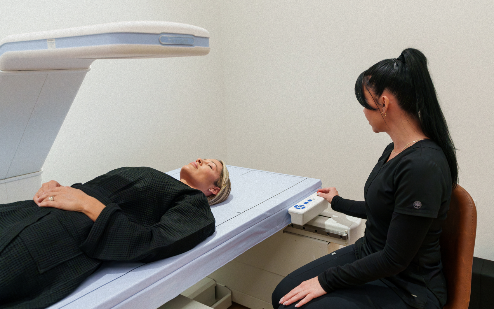 Patient on a DEXA scan table with a technician operating the imaging arm
