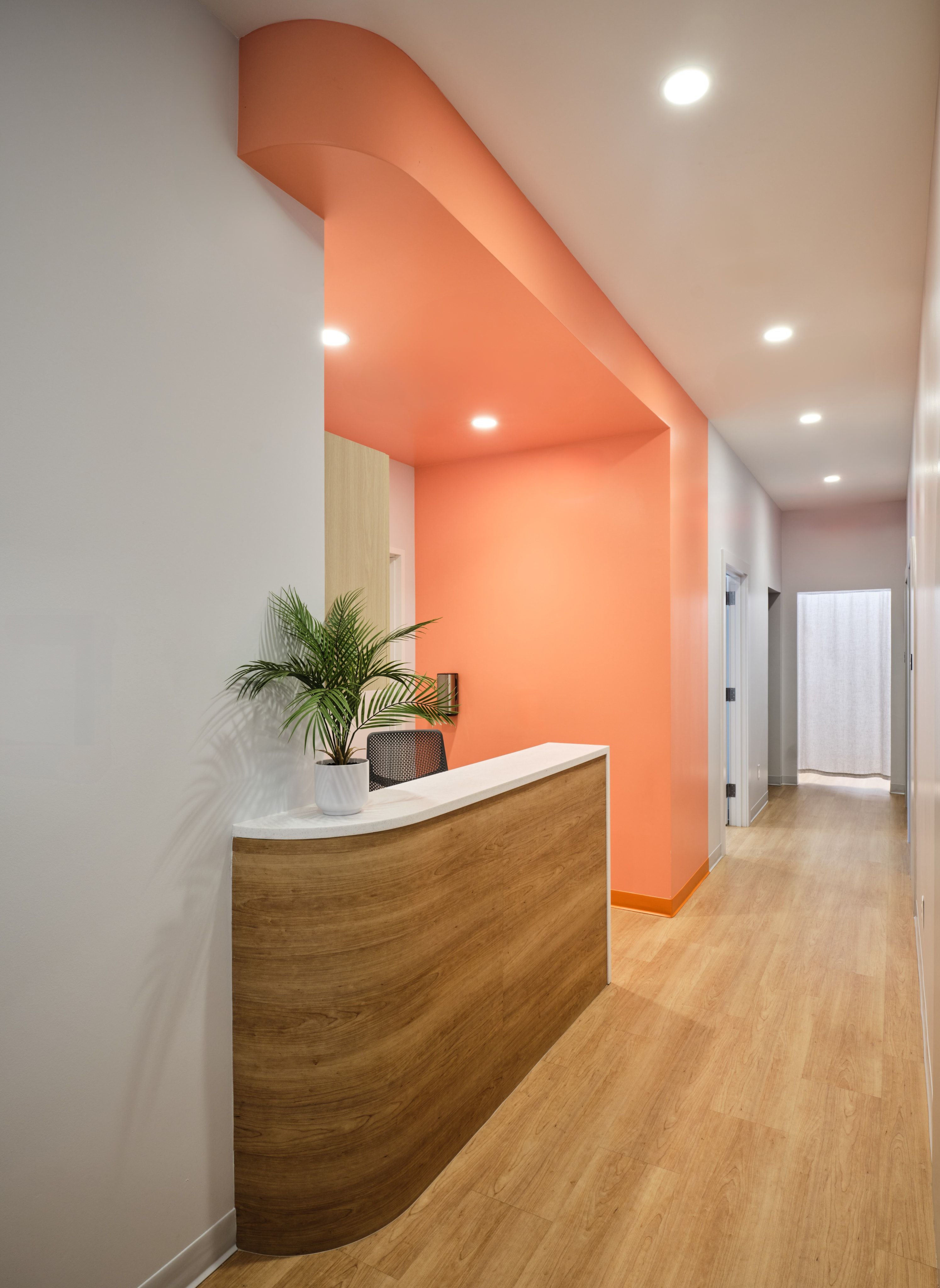 Coral reception desk with curved wood paneling in the Austin clinic