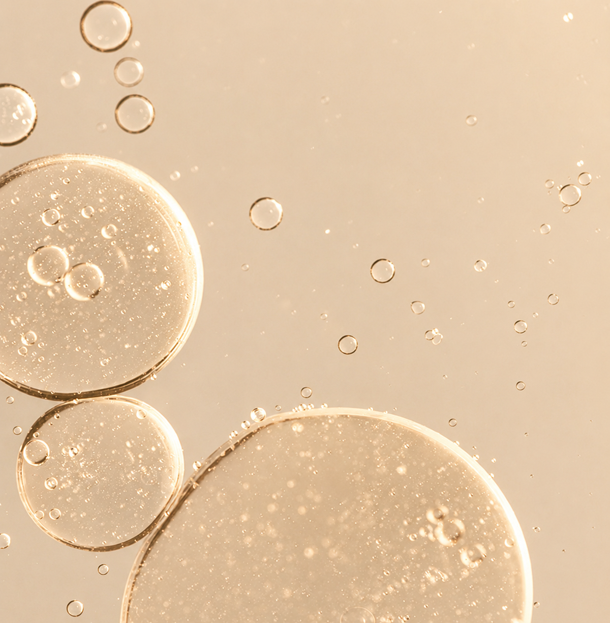 Translucent oil bubbles drifting across a warm beige background