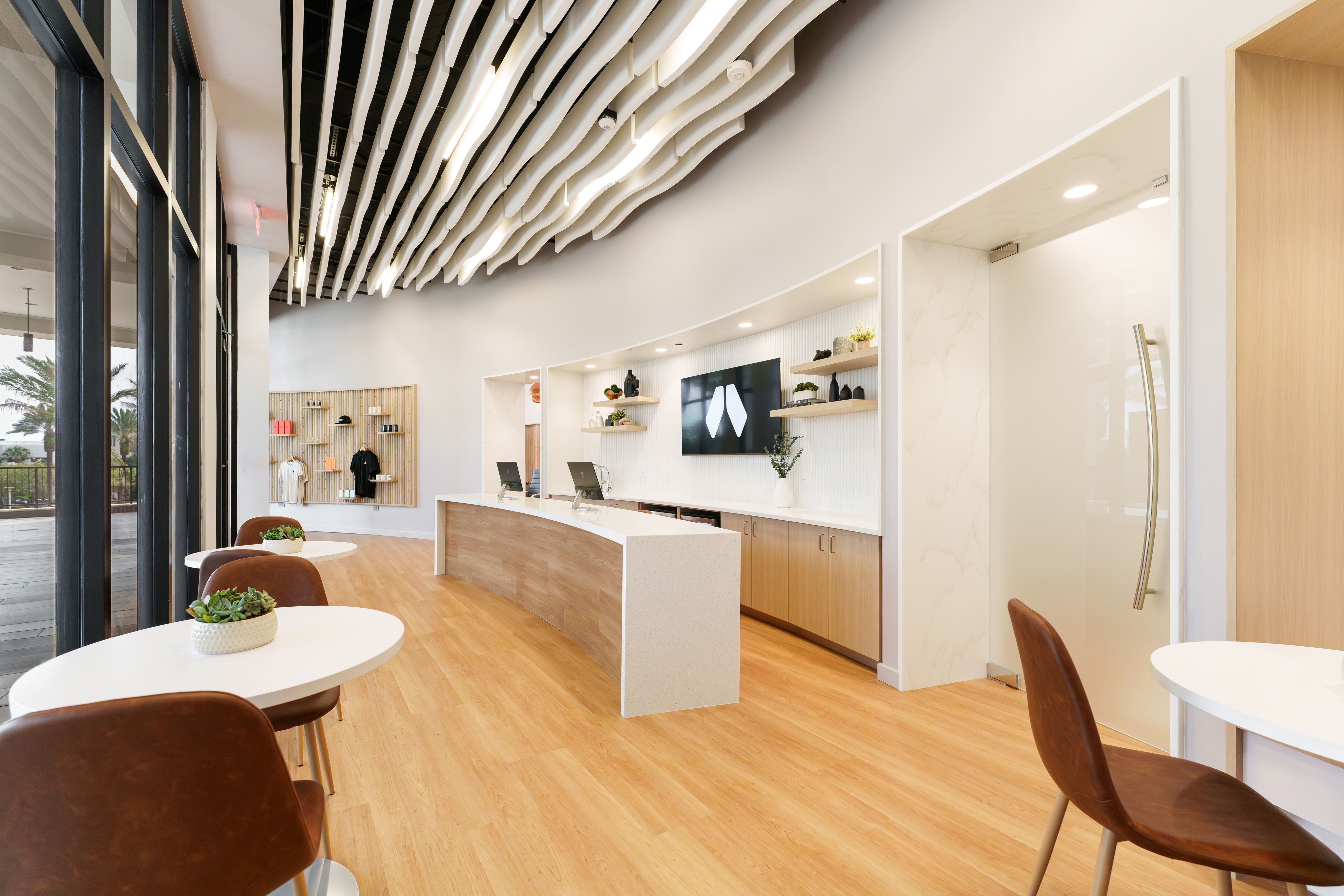 Sunlit reception desk with sculptural ceiling baffles and a relaxed lounge area