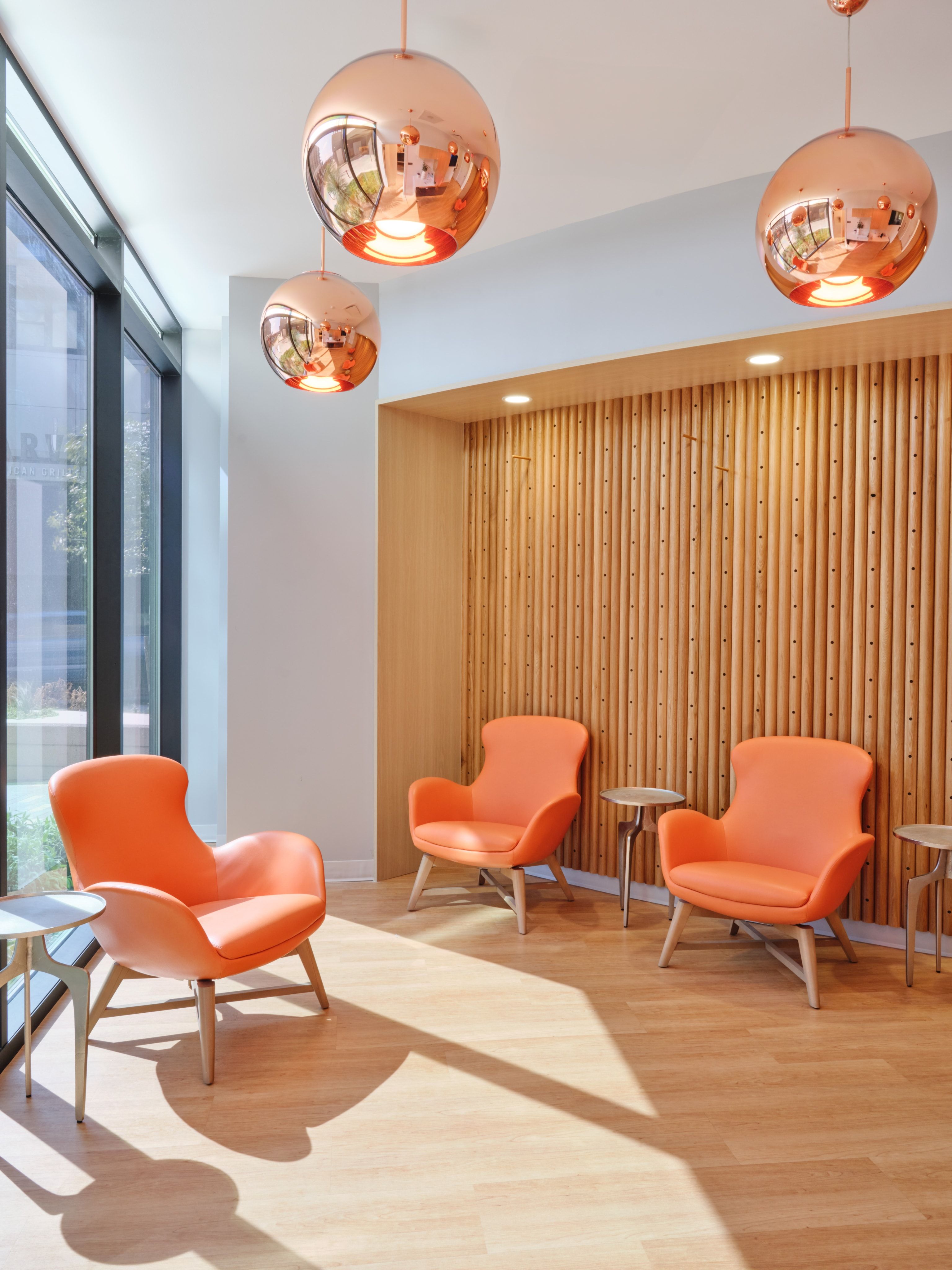 Lobby vignette with copper pendant lights and orange lounge chairs