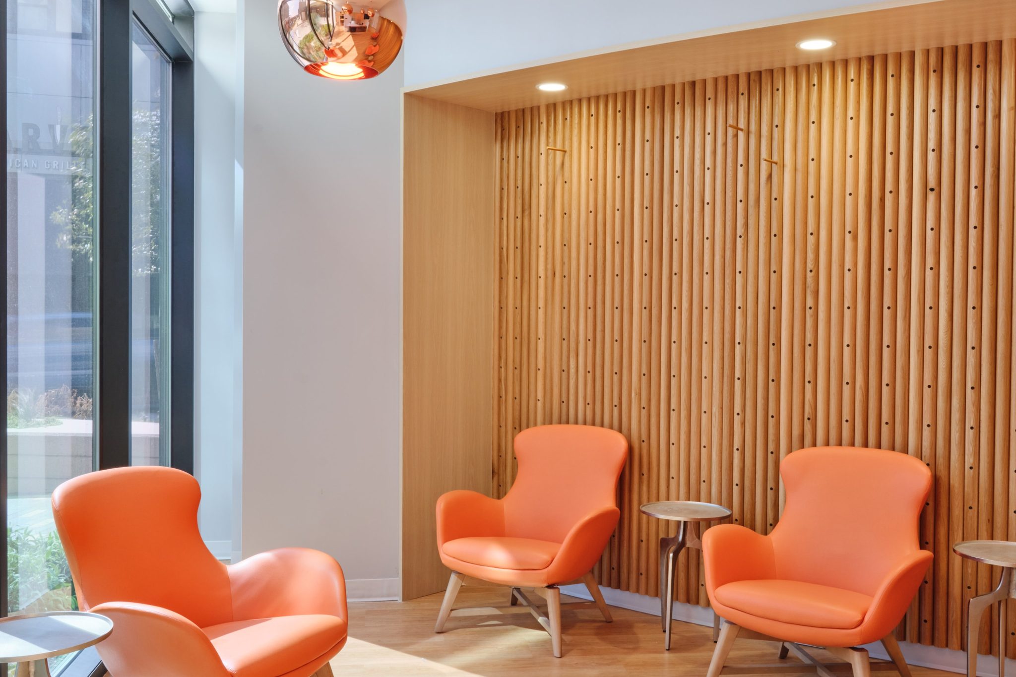 Lobby vignette with copper pendant lights and orange lounge chairs