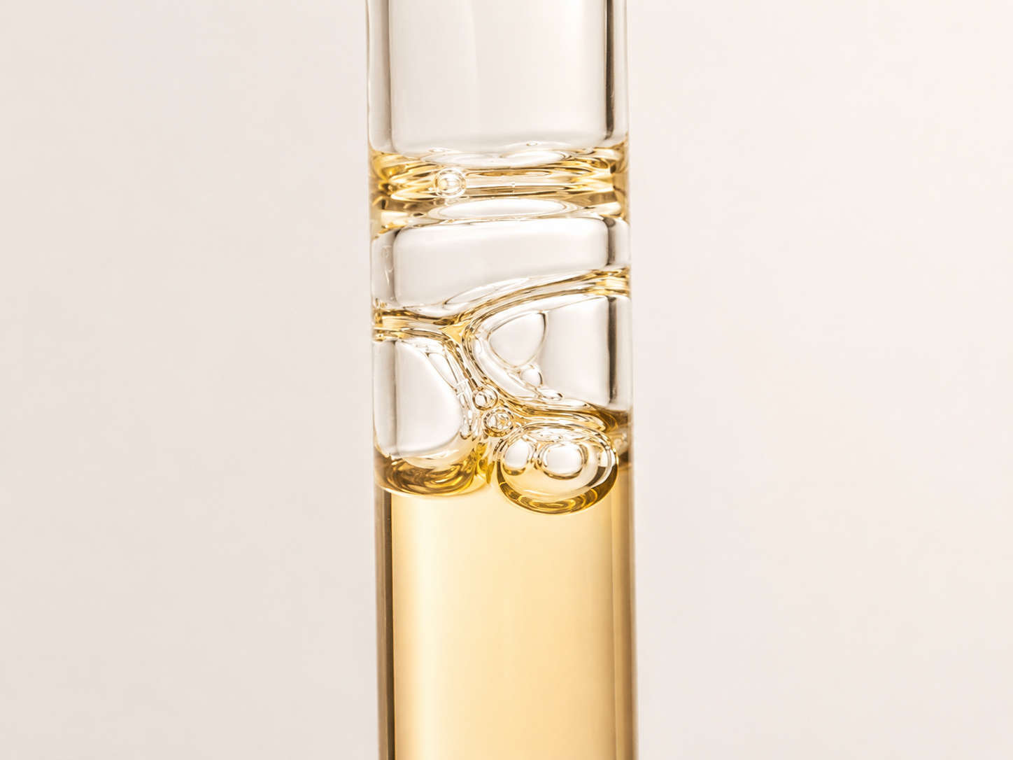 Cylindrical glass vessel with golden liquid suspended in soft side light