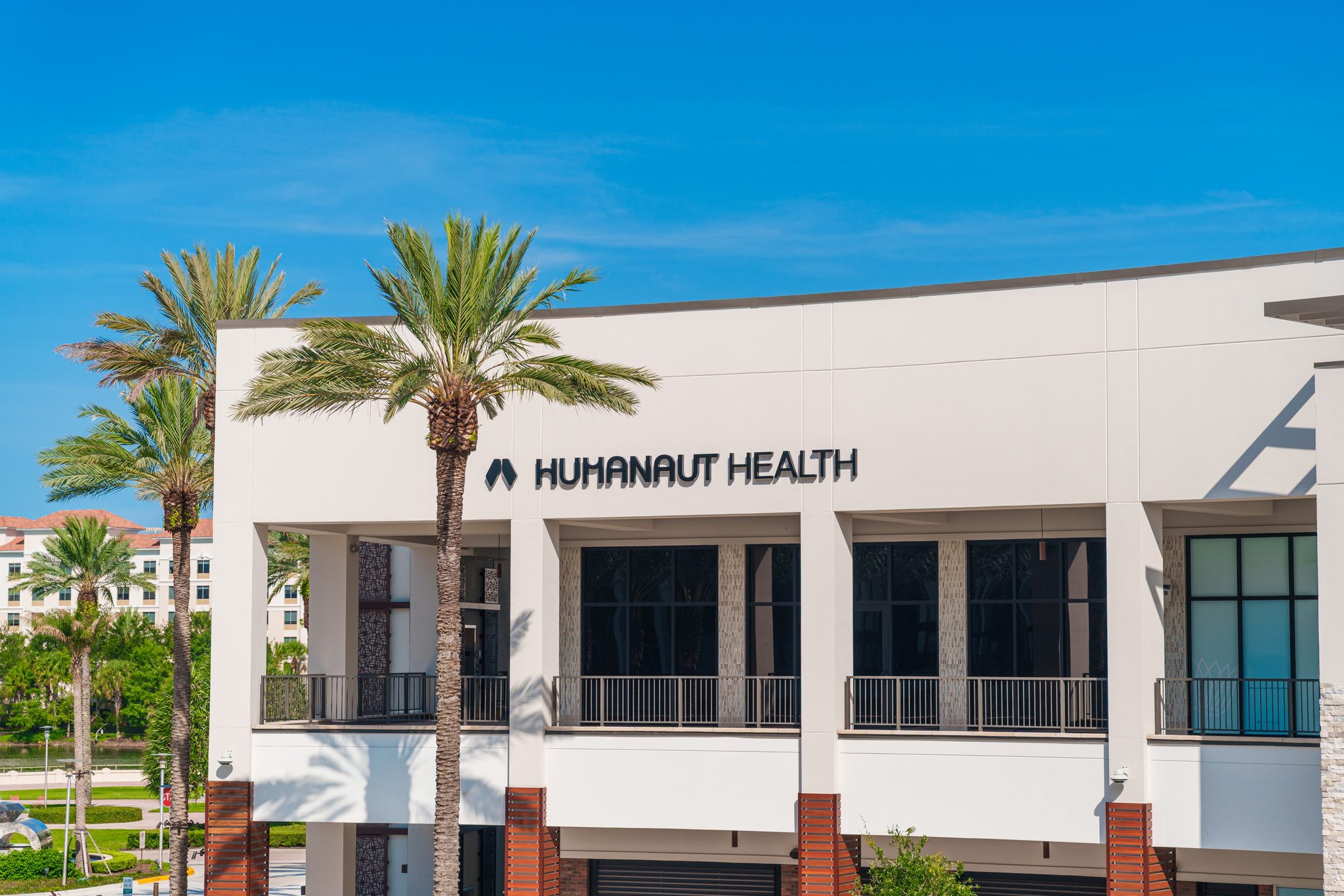 Exterior building elevation with palm trees and HUMANAUT HEALTH wordmark signage