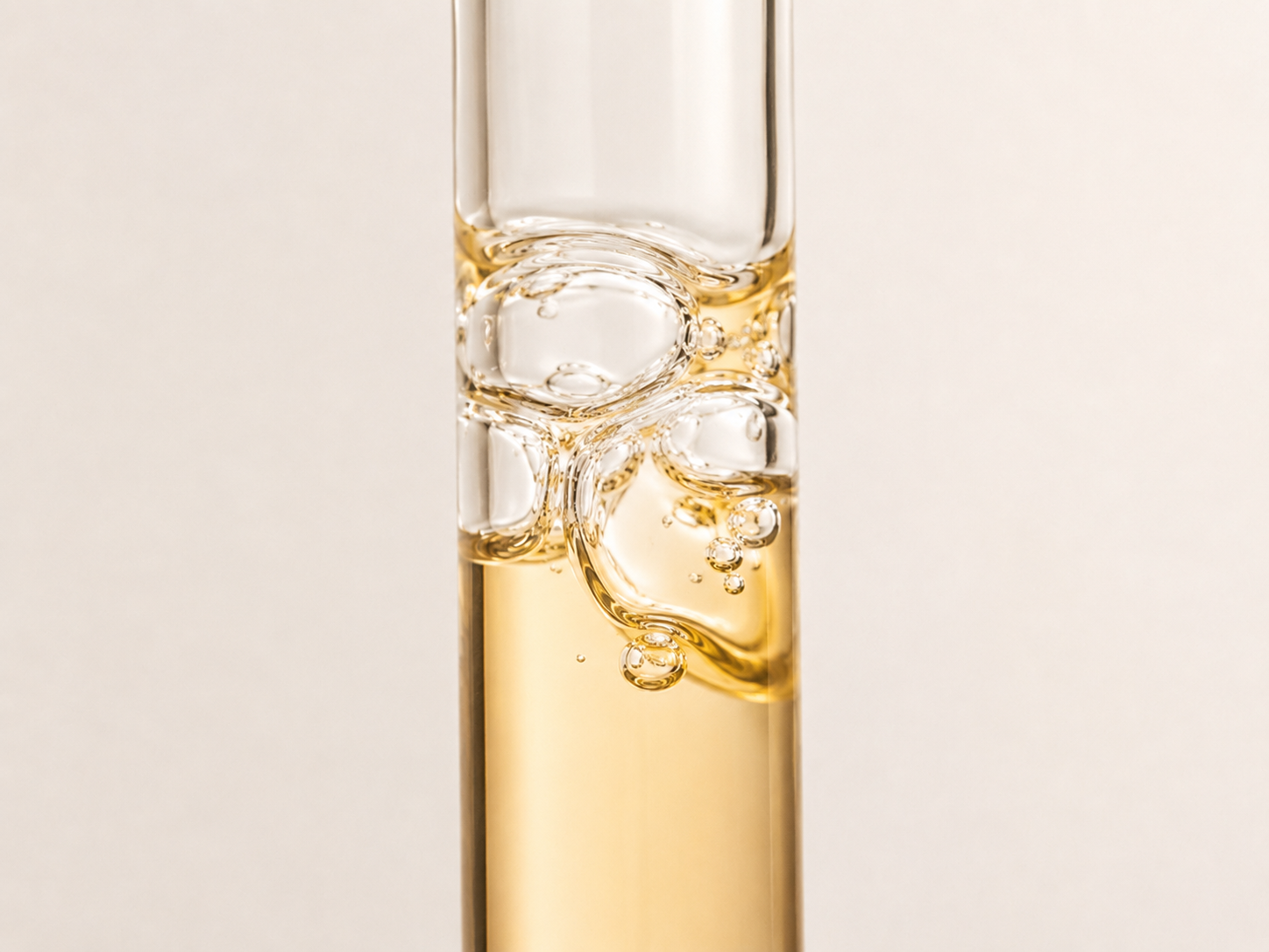 Backlit IV chamber with amber liquid against a soft gradient backdrop
