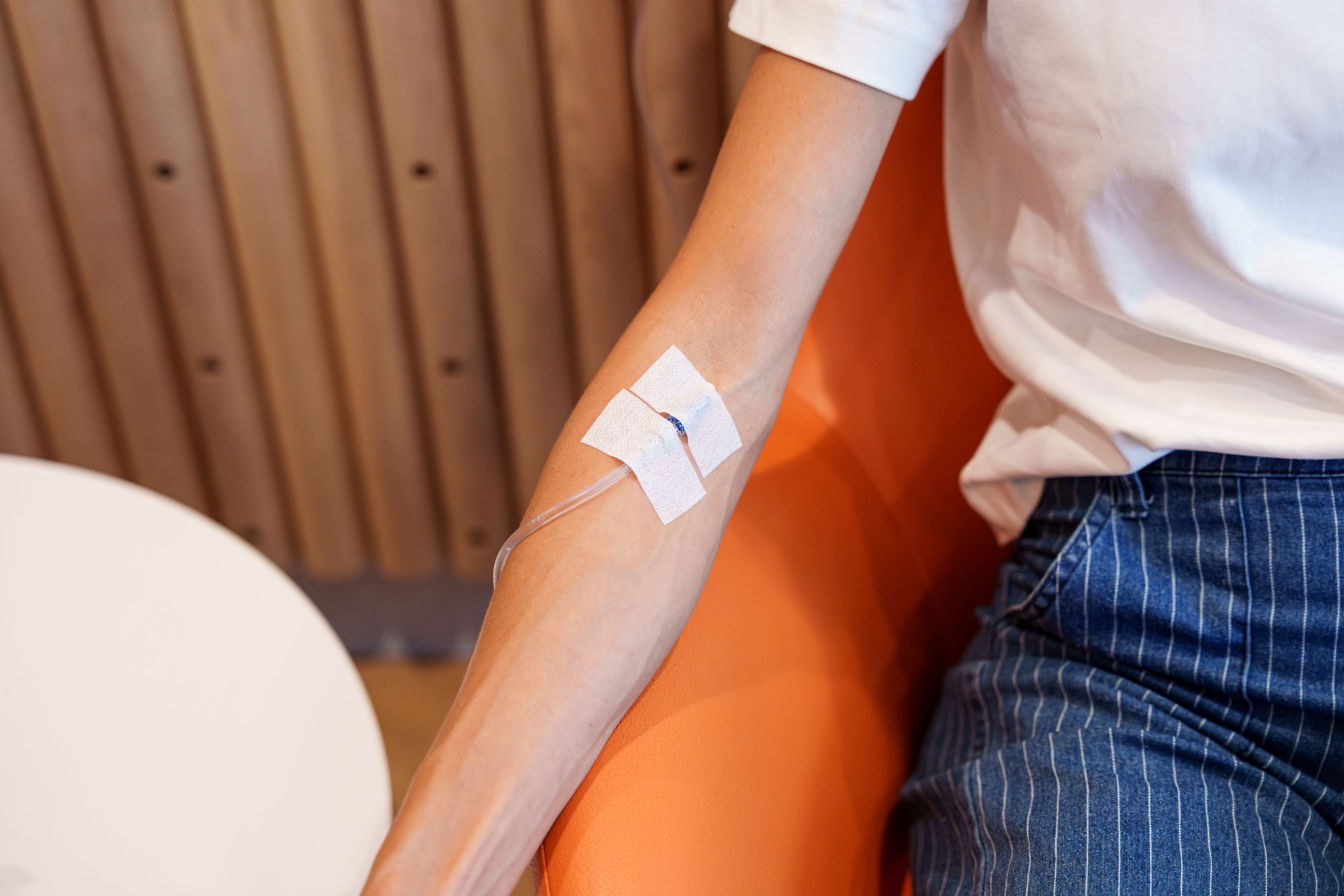 Close-up of an IV line taped to a patient's forearm in clinic