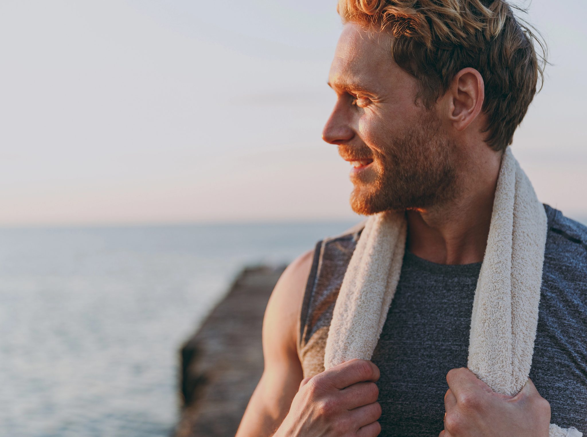 Coastal portrait of a man with a towel at sunset