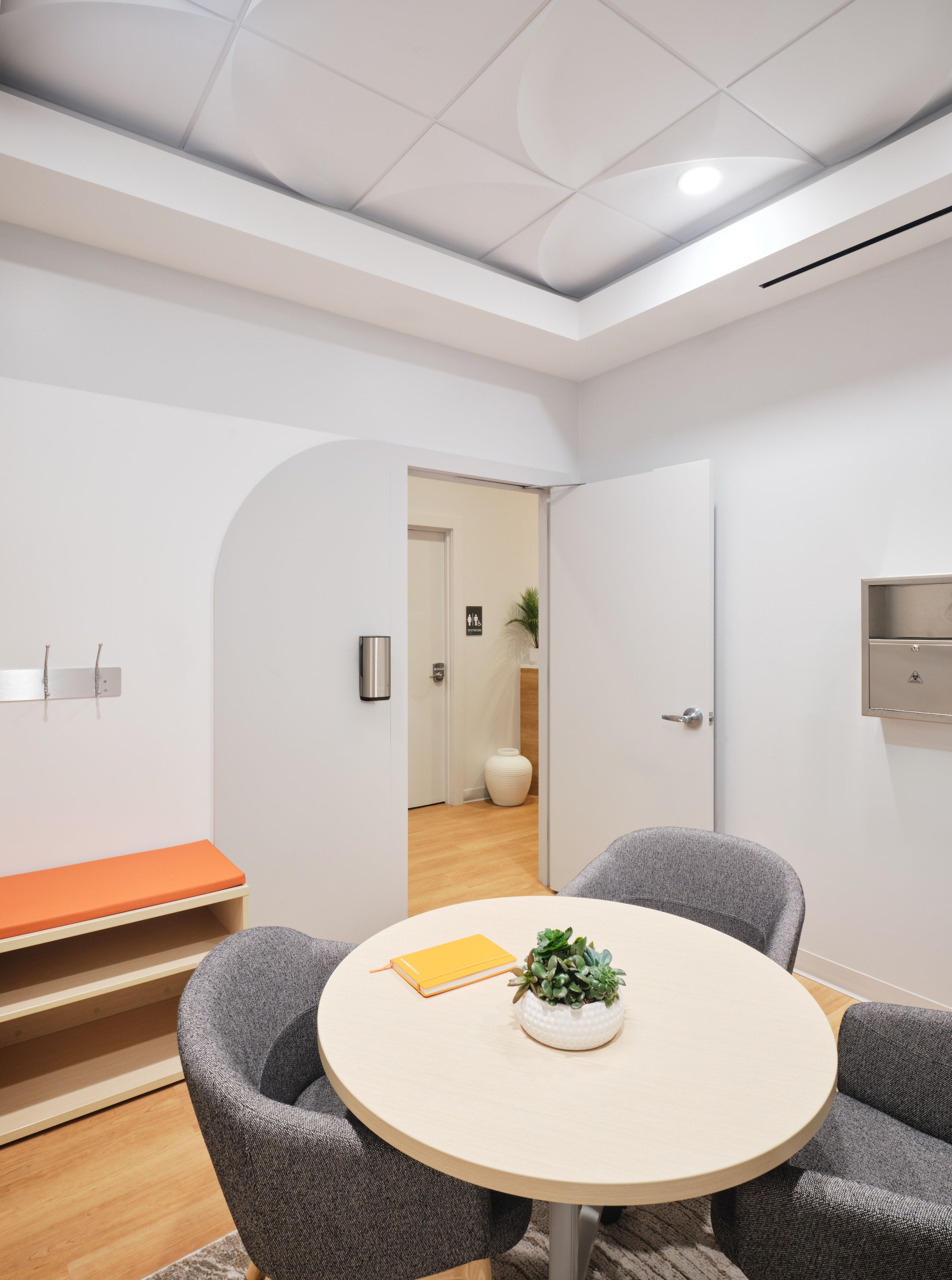 Consult room with round table and soft sculptural ceiling tiles