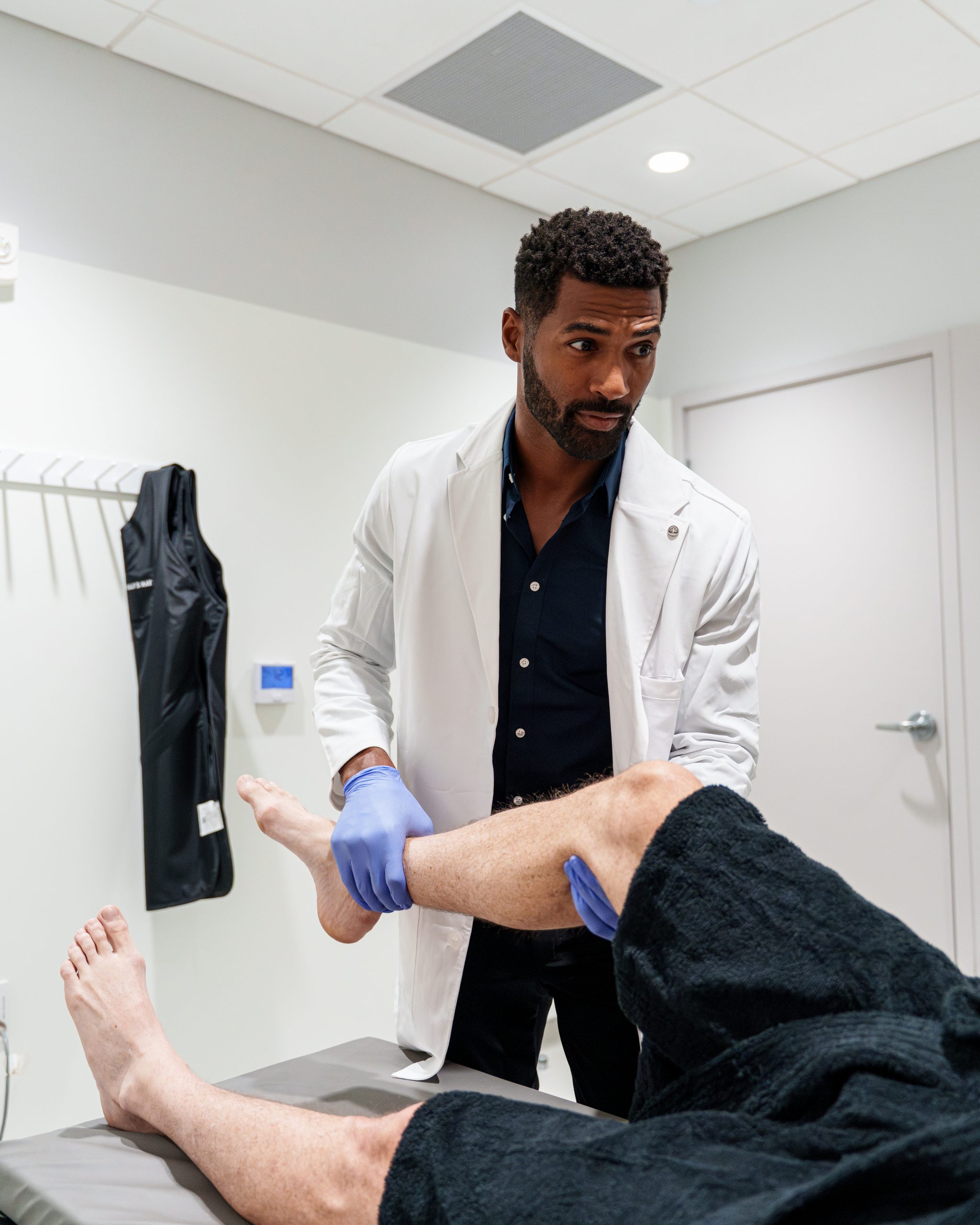 Humanaut physician examining a patient's leg in a treatment room