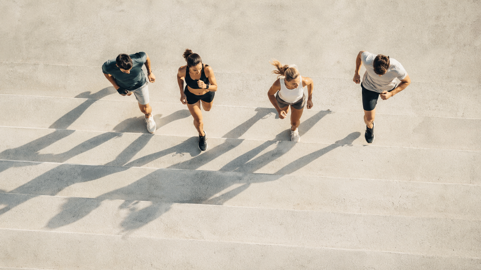 Aerial view of four runners on concrete steps casting long shadows